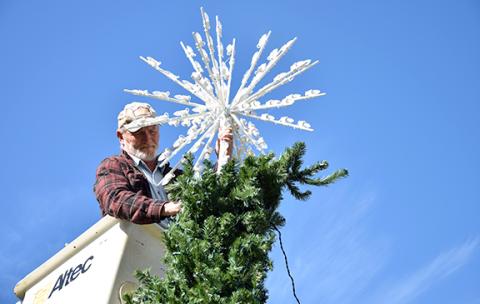Kyle Paris works to place the star atop the Canon City Christmas tree in the city park last week. The city will hold its tree lighting service Sunday at 6 p.m. at the park. (Photo by Sinclair)