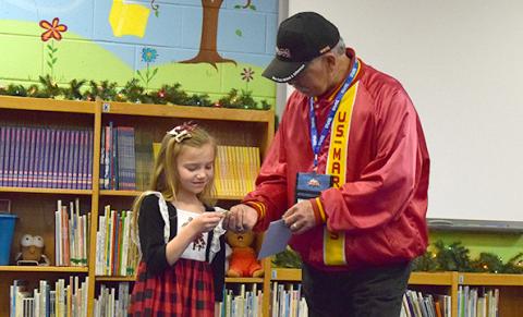 Toys for Tots Local Coordinator Mike Prather hands Bristol Patterson a Toys for Tots train pin to thank her for thinking of the organization during Carnesville Elementary School’s Pay It Forward project. (Photo by Sinclair)