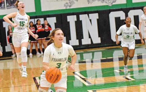 Kayleigh Chappell dribbles toward the basket as time runs out Friday night in the Franklin County Lady Lions’ overtime victory over Hart County in the Lions’ Den. Her teammates Emily Carson (No. 15) and Paris Gaye (No. 2) celebrate in the background. (Photo by Scoggins)
