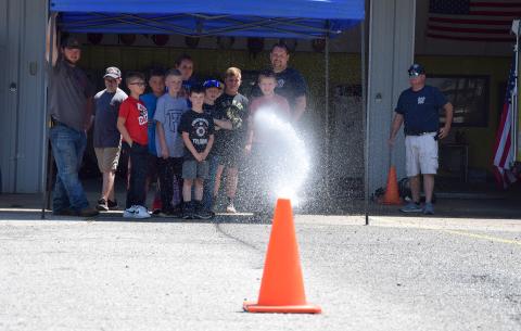 Mitchell Thurmond attempts to knock over a cone while using a fire hose during Junior Firefighter Day last week at the Carnesville Fire Department. (Photo by Sinclair)