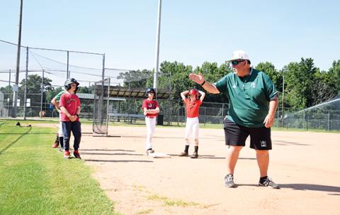 Coach David Skelly teaches campers where to look after running to first base during the second day of baseball camp. (Photo by Sinclair)