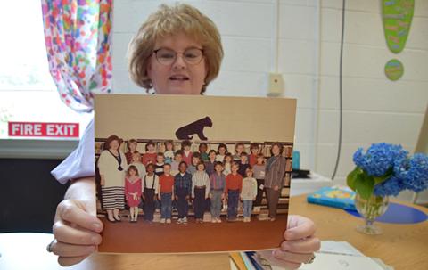 As she goes through her “forever file,” Robyn Moon finds the photo of the 28 “babies” in her first class of first graders. (Photo by Sinclair)