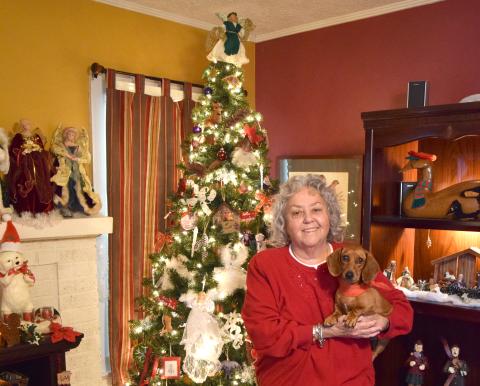 Marcia Millsap, with Duchess, stands in front of her Christmas tree, which is just one of the many decorations in her home. Millsap transforms the inside of her house each year into a holiday wonderland. For the complete story, see Page 12A. (Photo by Scoggins)