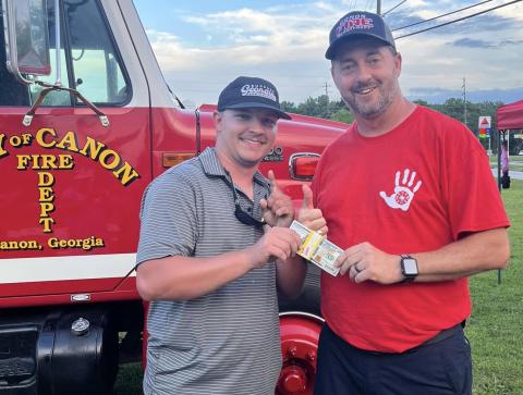 Jacob Tompkins (left) receives the $1,000 grand prize for winning the Canon Fire Department’s Touch the Truck event. Canon Fire Chief Lee Williams (right) presented the prize.