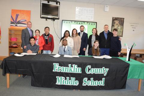 Franklin County Middle School held a signing ceremony Thursday for three students selected as REACH Scholars for the Class of 2029. Those in attendance were the REACH Scholars (seated from left) Khang Tran, Braylen Morrison and Selma Alicic, (standing, from left) FCMS Principal Dr. David Cawthon,; Trang Le and Kha Tran; Shanda Morrison; FCMS Assistant Principal Meredith Kilgore; FCMS Assistant Principal John David; and Mirzeta, Denis and Mirza Alicic. (Photo by Eavenson)