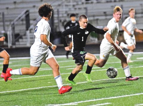 Lion Jonah Burger splits two Prince Avenue defenders on his way to a goal Friday night at Jeff Davis Field at Ed Bryant Stadium.