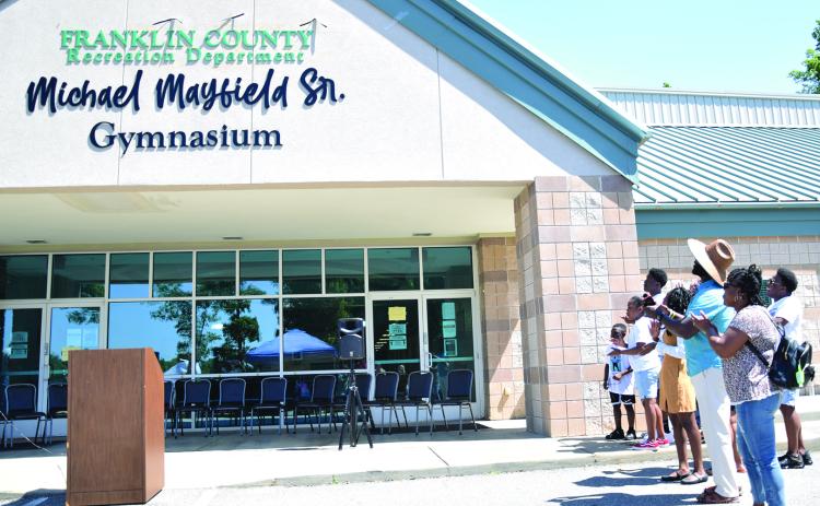 Members of the Mayfield family applaud after unveiling the sign proclaiming the new name of the gym at Rocky Ford Park as the Michael Mayfield Sr. Gymnasium. (Photo by Scoggins)
