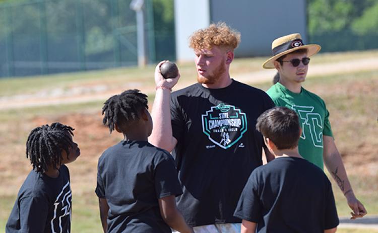 Keylan “Red” Rutledge, fresh off winning a AAA State Championship in shot put, gives pointers to future Lion athletes Tuesday during the Junior Olympics. (Photo by Scoggins)