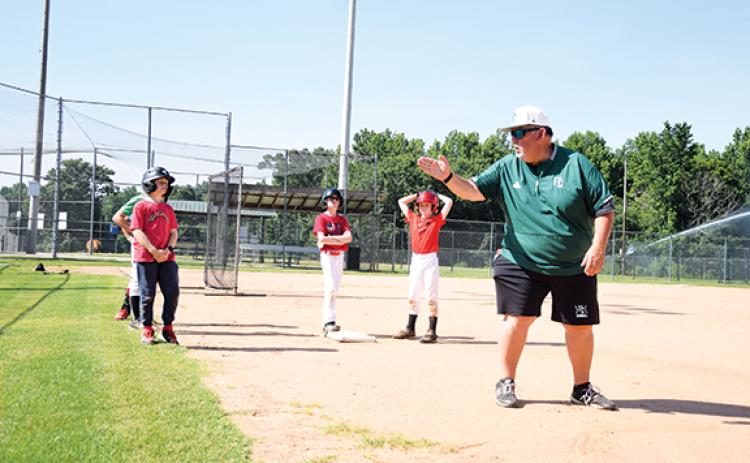 Coach David Skelly teaches campers where to look after running to first base during the second day of baseball camp. (Photo by Sinclair)