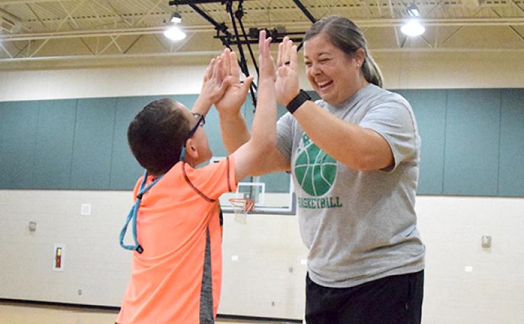Tripp Witherell gives Amber Adams high tens during physical education class at Carnesville Elementary School. He is one of the students Adams is working with in the Adaptive PE program. (Photo by Sinclair)