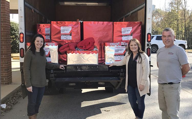 Franklin County Schools Social Worker Nikki Croy accepts a donation of coats and hoodies for Franklin County Schools from Harbin Lumber Company.