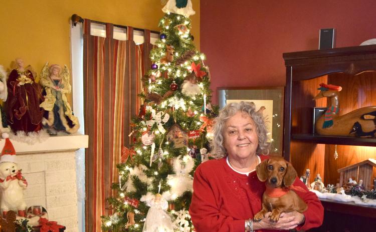 Marcia Millsap, with Duchess, stands in front of her Christmas tree, which is just one of the many decorations in her home. Millsap transforms the inside of her house each year into a holiday wonderland. For the complete story, see Page 12A. (Photo by Scoggins)