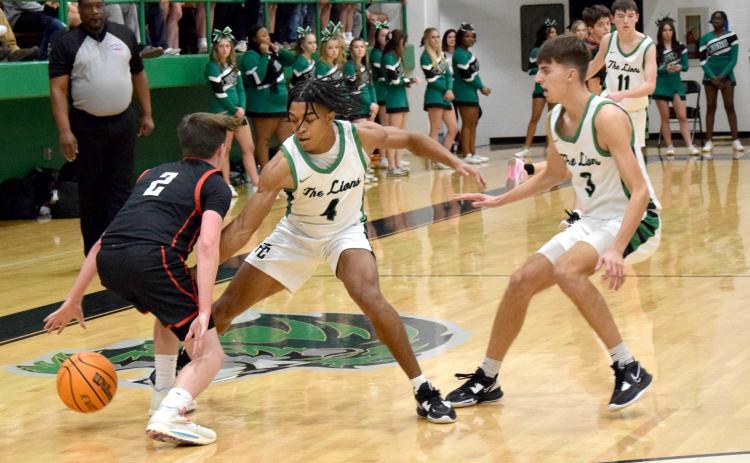 Jeloni Johnson (No. 4) and Cam Maxwell trap a Jackson County ballhandler during action Friday in the Lion’s Den. (Photos by Scoggins)
