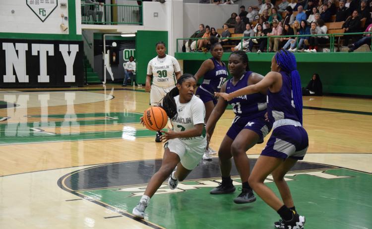 Paris Gaye drives by two Monroe defenders Tuesday in action at the Lion’s Den. Gaye had 23 points to lead the Lady Lions to a win.