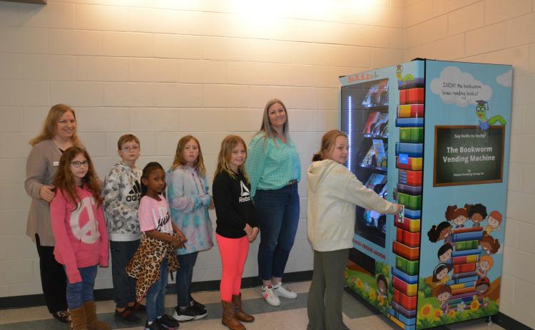 Students at Carnesville Elementary stand in line to try the new “Inchy” the Bookworm’s Book Vending Machine. The machines were recently placed in Carnesville, Royston and Lavonia Elementary Schools. The schools use the program as an incentive for the children to read more. Depending on the school, the rewards are based on behavior, attendance and/or grades. The eager readers are (from left) Freya Kolton, Will Cain, Jade Johnson, Keri Taylor and McKenna Carter. Looking on are (from left) Rita Shoemaker, dire