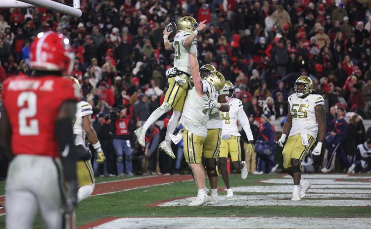 Keylan Rutledge lifts up Georgia Tech teammate and quarterback Haynes King after a touchdown against Georgia in Sanford Stadium. (Photo by Rose Scoggins)