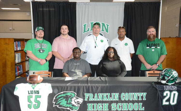 Antnez “Tank” Fortson (seated left) signed a college football scholarship to play for McPherson College in McPherson, Kan. Joining him at the signing ceremony at Franklin County High School last week were his mother, Breanda Fortson (seated right) and (back, from left) Franklin County Lion football coaches Caleb Hardy, Zach Marinell, Head Coach Chuck Holland, Robert Allen and Cayman Brooks. (Photo by Eavenson)