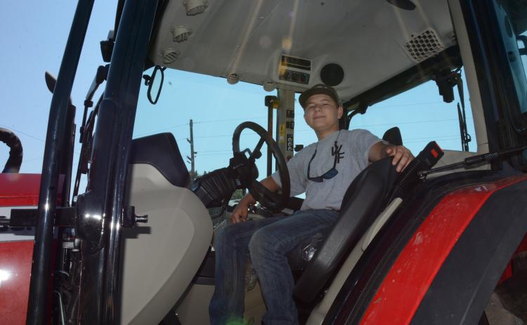 14-year-old Heaton Williams sits in his Massey Ferguson tractor that he uses ion his family’s farm and to bush hog fields and harvest corn for local farmers. (Photo by Charlie Eavenson)