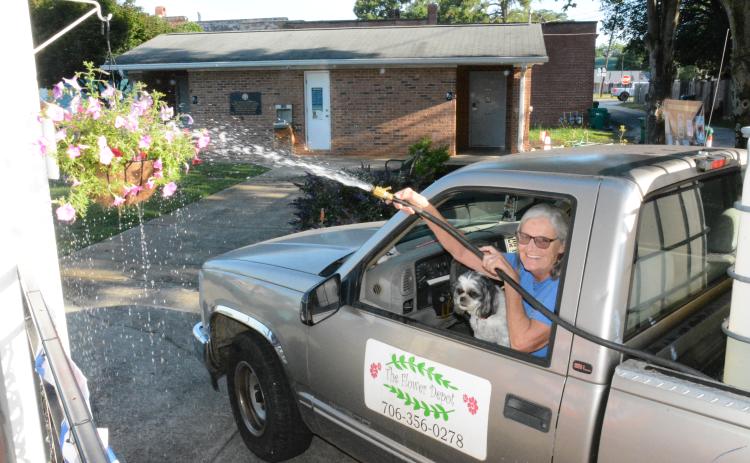 Diane Holmes can water most of Lavonia’s hanging baskets and flower pots from her truck with the help of her little dog, Dottie. (Photos by Charlie Eavenson)
