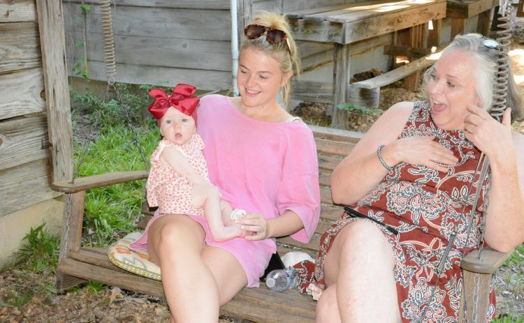 Rebecca Milford Floyd laughs at the antics of little Landrie Armour, who is being held by her mother Alyssa Ellard.