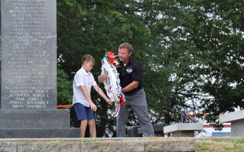 Dusty Morgan and son Shiloh lay a wreath during Memorial Day ceremonies Monday in Carnesville