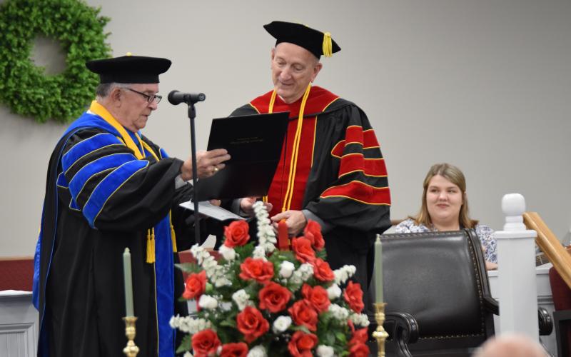 Dr. Ronnie Simpson of Macedonia Bible College presents Dr. Dan Bailey with his diploma during a ceremony Saturday at Abundant Life Baptist Church in Hartwell, where Bailey is a member and Sunday School teacher. (Photo by Scoggins)