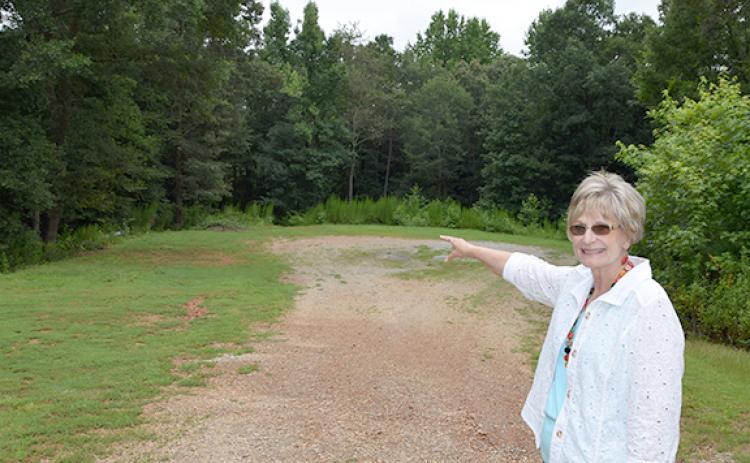 Dr. Beverly Oxley shows where trees will be cleared for The Ark Family Preservation Center’s facility. The road for the Wellsprings campus will be extended to a cul-de-sac, and the facility will be built to the left, adjacent to the playground built about two years ago. (Photo by Sinclair)