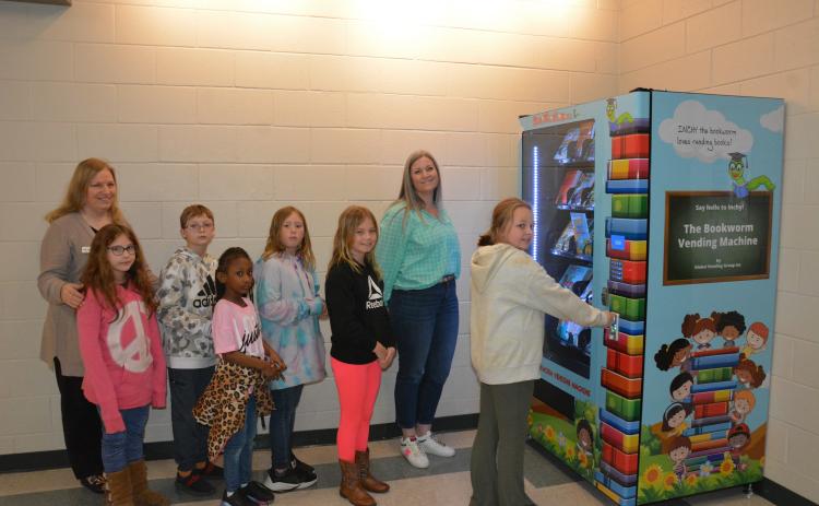 Students at Carnesville Elementary stand in line to try the new “Inchy” the Bookworm’s Book Vending Machine. The machines were recently placed in Carnesville, Royston and Lavonia Elementary Schools. The schools use the program as an incentive for the children to read more. Depending on the school, the rewards are based on behavior, attendance and/or grades. The eager readers are (from left) Freya Kolton, Will Cain, Jade Johnson, Keri Taylor and McKenna Carter. Looking on are (from left) Rita Shoemaker, dire
